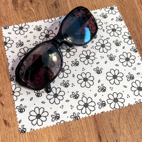 Micrfofastertuch für Brillen und Displays, hier mit Muster Bienen und Blumen. Auf dem Tuch liegt eine Sonnenbrille.
